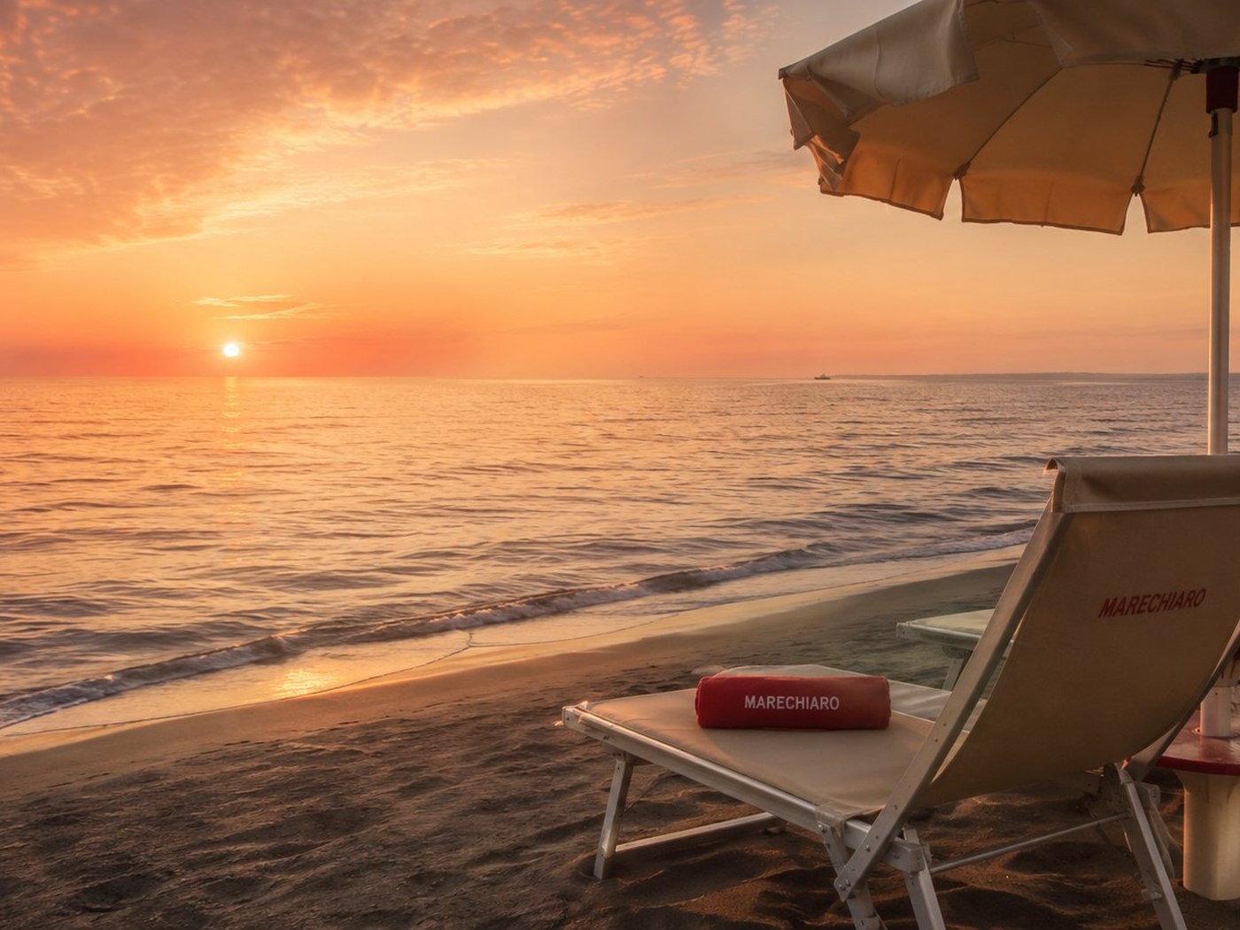 Lettino Marechiaro al tramonto sulla spiaggia di Ostia, con ombrellone e mare